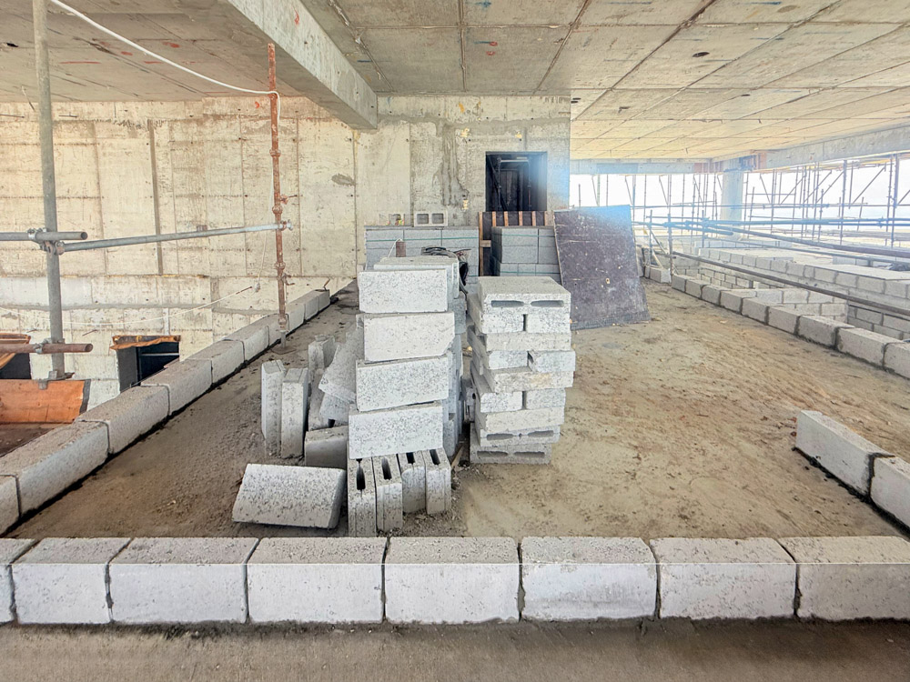 Beach Walk Iii By Imtiaz An unfinished construction site with stacked concrete blocks and scaffolding, featuring exposed walls and flooring.